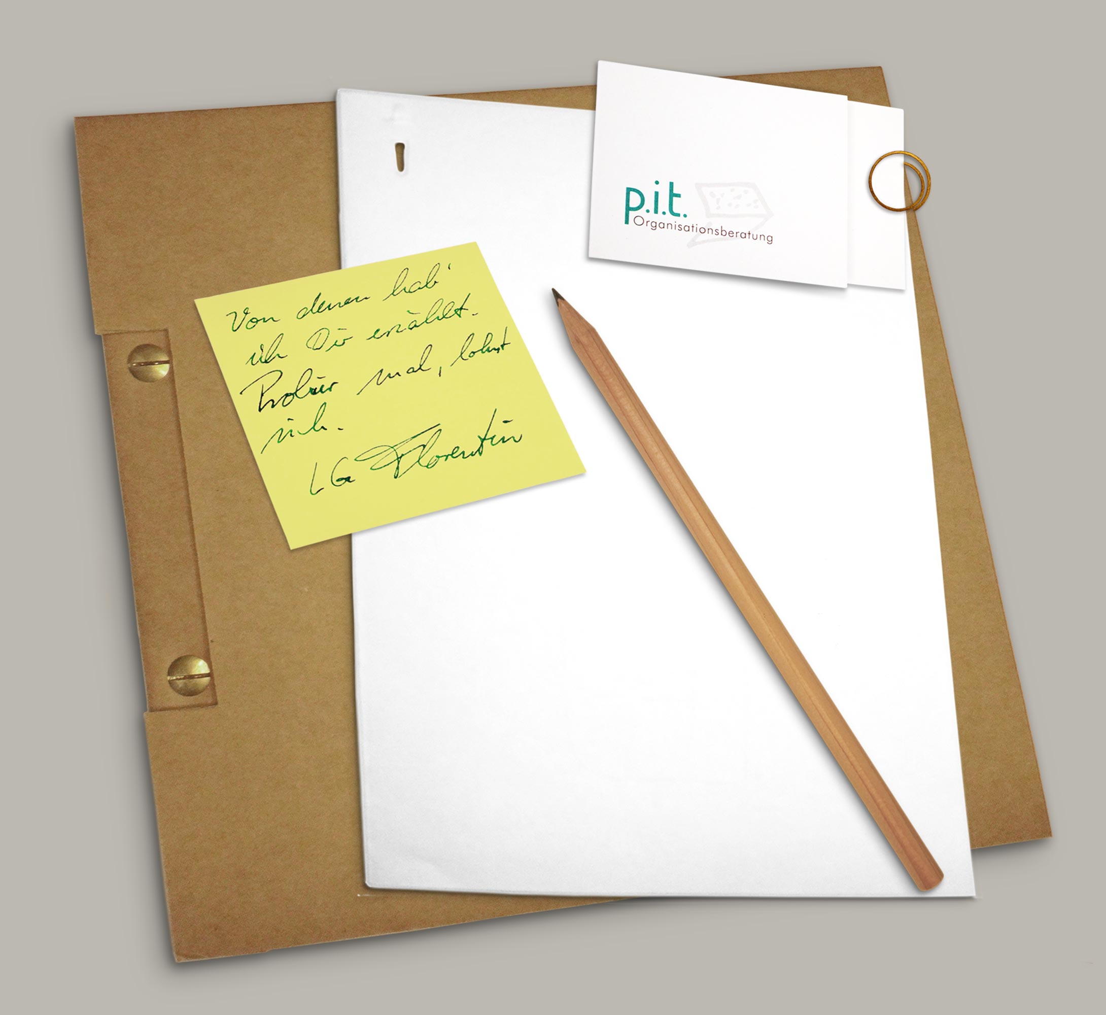 Foto von einer Mappe aus Naturkarton, darauf ein Blatt Papier mit Bleistift, eine p.i.t.-Visitenkarte und ein Post-it mit der Notiz: „Von denen hab' ich Dir erzählt. Probier mal, lohnt sich. LG Florentin