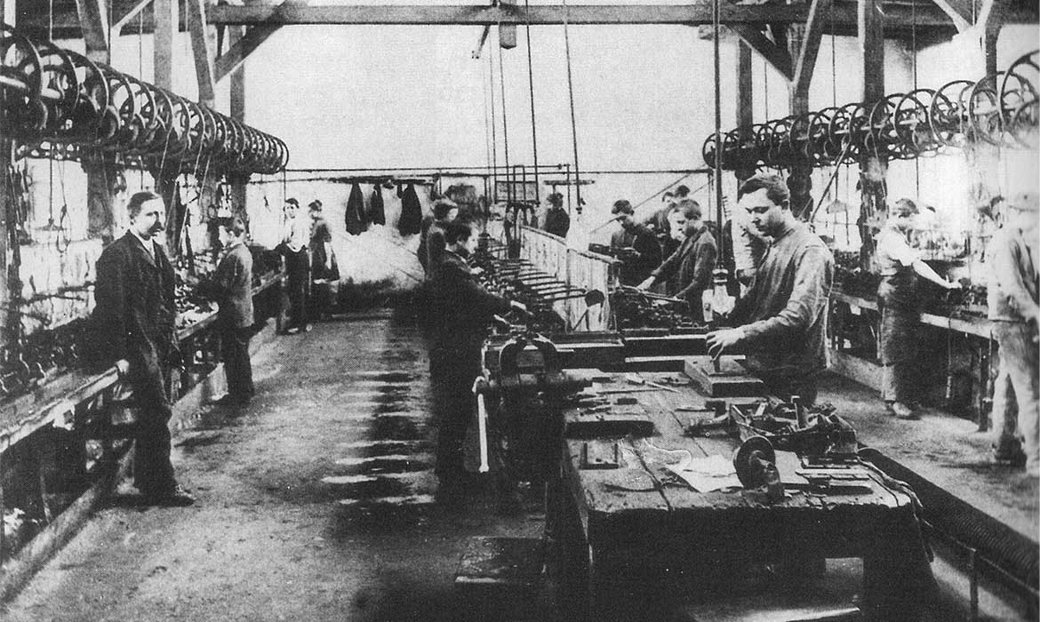 historisches Foto einer Kammsägerei in Betrieb; ein Mann im Anzug steht nur da und scheint der Vorarbeiter oder Chef zu sein.