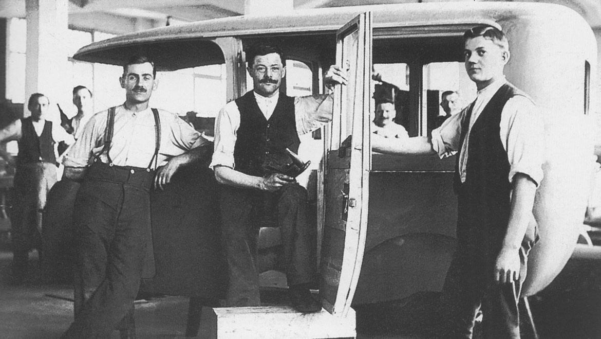 Historisches Foto: drei Männer posieren vor einem Oldtimer