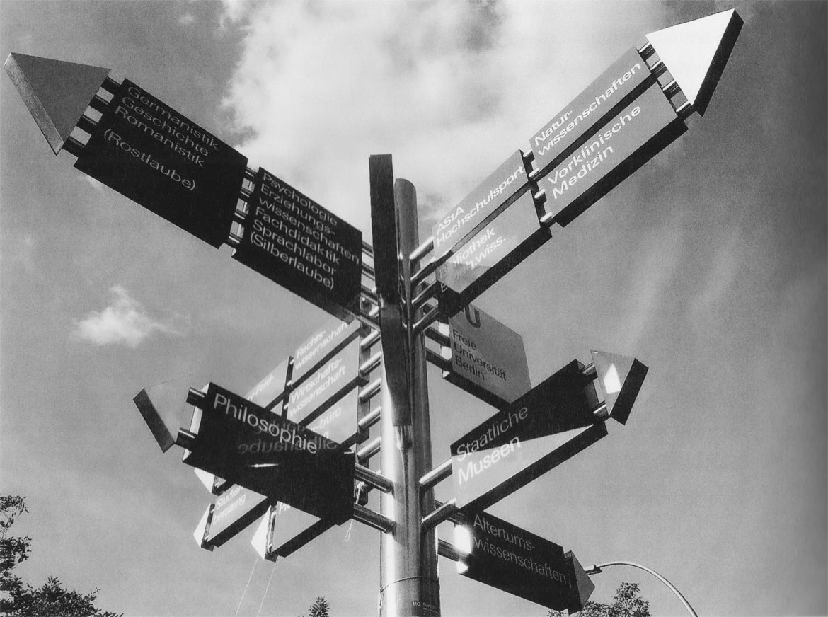 Wegeleitsystem einer Uni: beschriftete Schilder in Pfeilform zeigen in alle Himmelsrichtungen